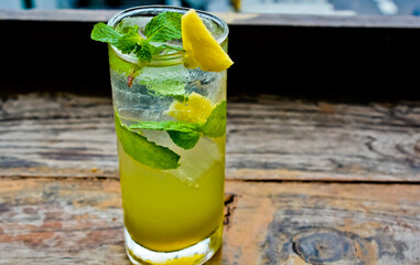 Fresh drink pineapple juice with lemon leaves on wooden table