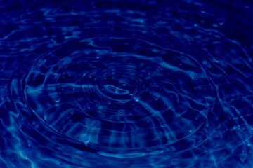 Bluewater waves on the surface ripples blurred. Defocus blurred transparent blue colored clear calm water surface texture with splash and bubbles. Water waves with shining pattern texture background.	