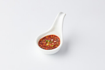 Thai chili sauce (Nam jim jaew) served on white spoon cup isolated on white background. It’s made with fish sauce, sugar, and lime, good for grilled meats. spicy, sweet, salty and sour taste.