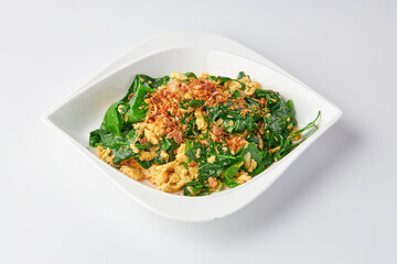 Stir-fried Malindjo Leaves with Egg top with Fried garlic served on white plate isolated on white background.