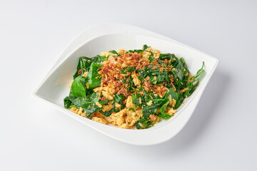 Stir-fried Malindjo Leaves with Egg top with Fried garlic served on white plate isolated on white background.