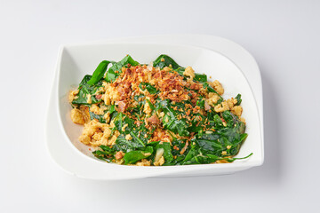 Stir-fried Malindjo Leaves with Egg top with Fried garlic served on white plate isolated on white background.