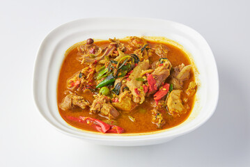 Chicken jungle curry served in white bowl isolated on white background. Hot and spicy chicken soup with herbs and vegetable Thai style.