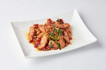 Thai spicy stir-fried grilled pork neck (Pork Jowl) with holy basil leaves served in white plate isolated on white background. Hot and spicy.