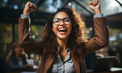 Happy young female employee sitting on office chair, raising arms and making winner gesture, very happy and excited. - Powered by Adobe