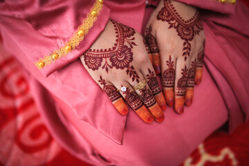 Henna on bride's hands with wedding rings. Selective focus. Image close up.