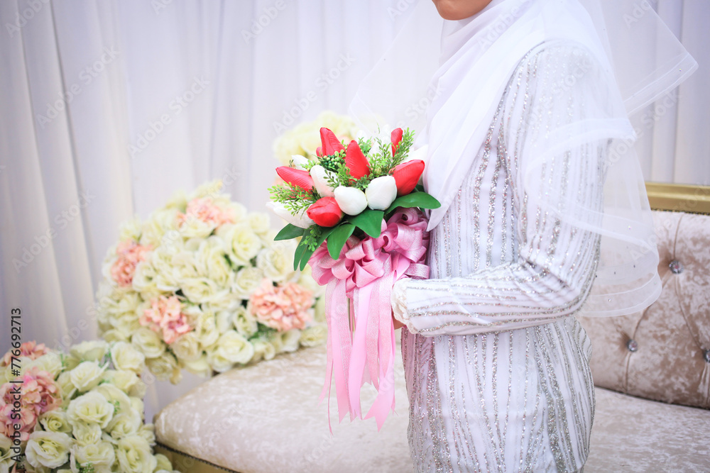 Wall mural Beautiful bouquet of different colors in the hands of the bride in a white dress. Bride holding her bridal bouquet.