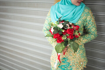 Malay bride holds a wedding bouquet, wedding dress, wedding details. Close up image.