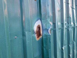 Hole with rust on a metal fence