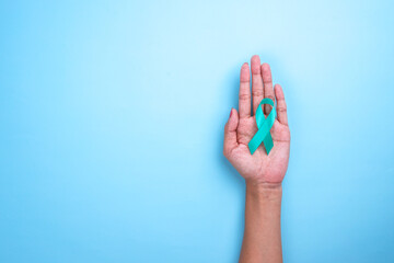 Ovarian Cancer Month, Cervical Cancer Day. Close-up Teal Awareness Ribbon on Woman Hands to Support Cancer Survivor.