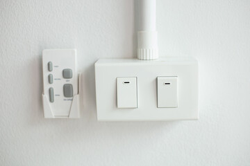 Twin white light switches mounted on the wall near the remote control.