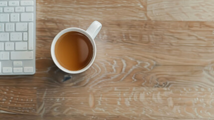 Obraz na płótnie Canvas Overhead view of a white coffee cup near a minimalistic white keyboard on a wooden desk