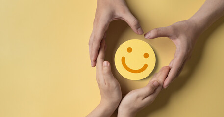 paper cut smiley face in hands of a cancer sick person on yellow background. world cancer day,...