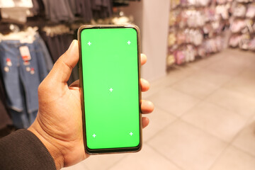 holding smart phone with green screen against shopping mall background 