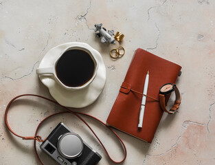 Travel mood - a cup of coffee, a retro-style camera, a notebook on a marble table in a cafe, top view