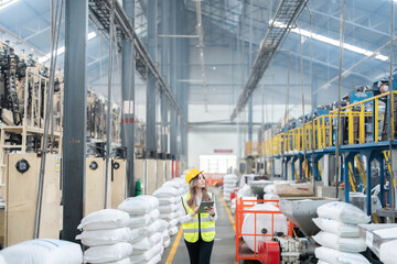 Wide angle shot in warehouse with Asian female engineer, maintenance supervisor wearing a hard hat...