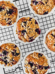 Close up blackcurrant muffins with oatmeal crumble on a baking rack on a light background, top view