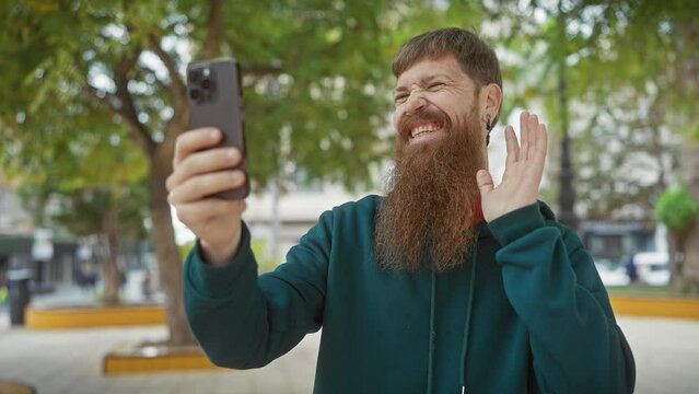 A cheerful, bearded redhead man takes a selfie outdoors on a sunny day, enhancing features like technology, lifestyle, and nature.