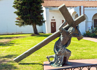 A statue of a Cross in front of the Spanish-Californian Mission San Luis Rey de...