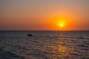 Vibrant sunset at Playa Blanca, Baru, with a boat silhouette against the tranquil sky, capturing the scenic atmosphere of Cartagena, Colombia