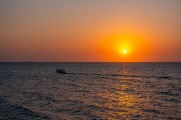 Vibrant sunset at Playa Blanca, Baru, with a boat silhouette against the tranquil sky, capturing...