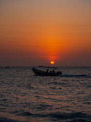 Obraz premium Sunset at Playa Blanca, Baru, with a boat silhouette against the tranquil sky, capturing the scenic atmosphere of Cartagena, Colombia