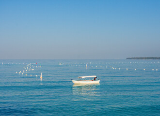 Serene view at Playa Blanca, Baru with a lone boat floating on the calm blue sea, clear sky above, and buoy markers in the water