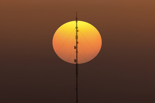 Antenna tower of telecommunication and Phone base station with TV and wireless internet antennas at sunset
