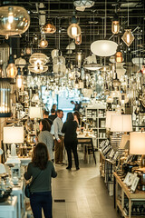 Fototapeta premium Excitement of customers testing lamps and desk lights, surrounded by lighting fixtures in a well-stocked store.