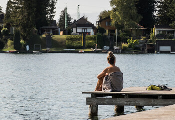 woman sitting in bath towel on a jetty in the sun