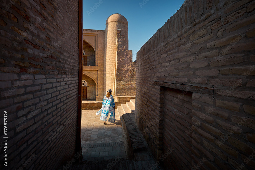 Wall mural tourist woman in ethnic dress at narrow street in ichan kala of khiva