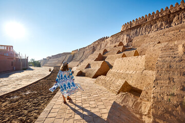 Tourist woman in ethnic near city wall in Khiva