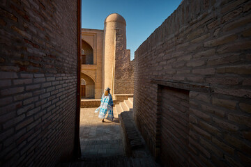 Tourist woman in ethnic dress at narrow street in Ichan Kala of Khiva - 776879126