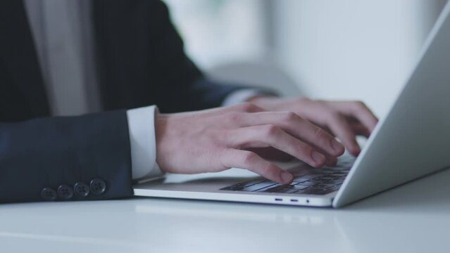 オフィスでパソコンを使って仕事をするスーツを着た若い日本人ビジネスマン	