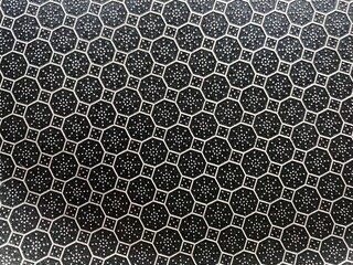 Close up of a hexagonal pattern on a black metal surface.
