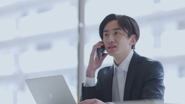 オフィスでパソコンを使って仕事をするスーツを着た若い日本人ビジネスマン
