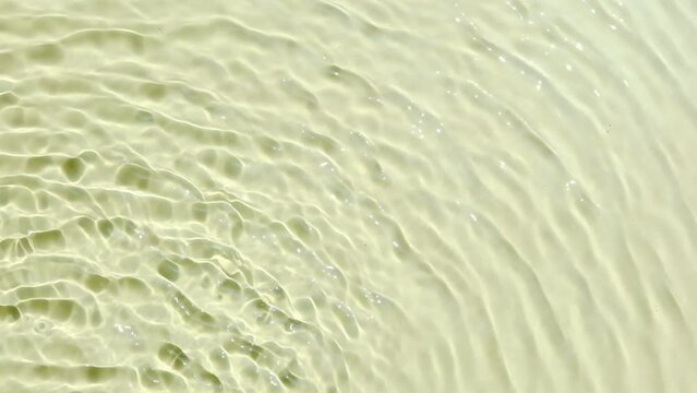 Background summer natural beige texture, clear water with ripples and splashes. Water waves in sunlight with leaf shadow, and background concept of cosmetics, moisturizer, and toner.	
