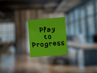 Post note on glass with 'Play to Progress'.