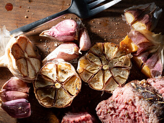 Cut steak and roasted garlic on a cutting board