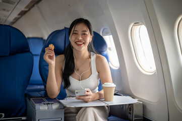 A female passenger is enjoying snacks and listening to music on her headphones during the flight.