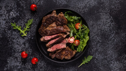 Grilled beef steak with spices on a black plate