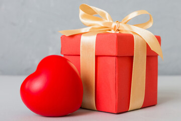 gift box with red bow and red heart on colored background. Perspective view. Flat lay