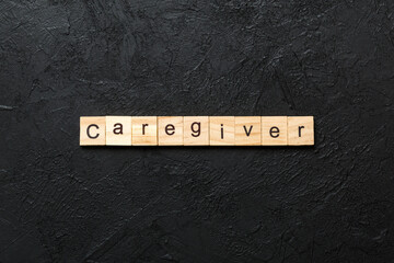 Caregiver word written on wood block. Caregiver text on table, concept