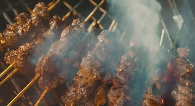 Satay being cooked over a fire, pieces of skewered meat being grilled. delicious Asian food