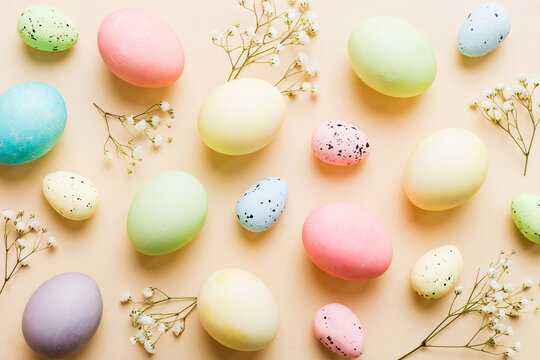 Happy Easter composition. Easter eggs on colored table with gypsophila. Natural dyed colorful eggs background top view with copy space