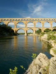 Papier Peint photo autocollant Pont du Gard Pont du Gard famous aqueduct arched bridge mirroring in Gardon river, popular tourist landmark in France