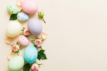 Happy Easter. Easter eggs on colored table with yellow roses. Natural dyed colorful eggs background top view with copy space