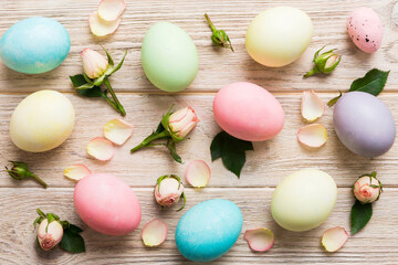 Happy Easter. Easter eggs on colored table with yellow roses. Natural dyed colorful eggs background top view with copy space