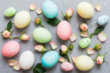 Happy Easter. Easter eggs on colored table with yellow roses. Natural dyed colorful eggs background top view with copy space