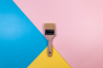 Top view of paint brush on colourful background. Blue, pink and yellow background. Colourful...